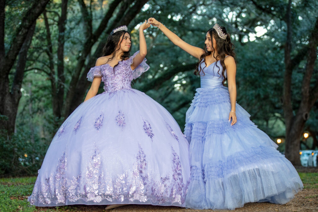 Romina and Camilla holding hands in ballgowns during a joint Quinceañera photoshoot at Rice University in Houston